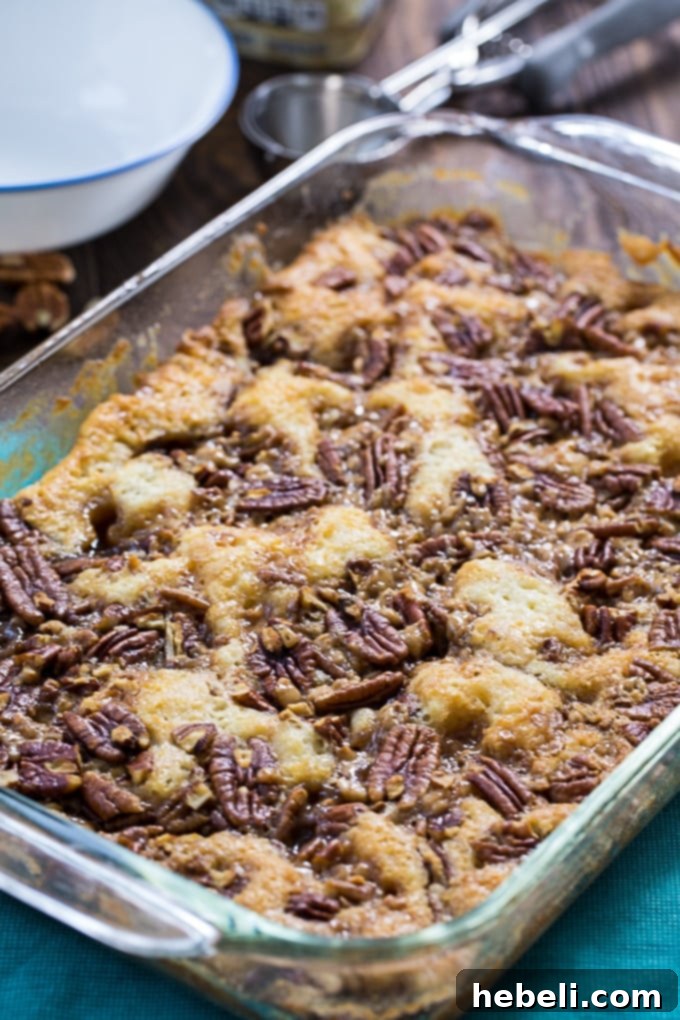 Pecan Pie Cobbler baking in a 9x13-inch pan, showcasing its golden-brown topping and rich texture.
