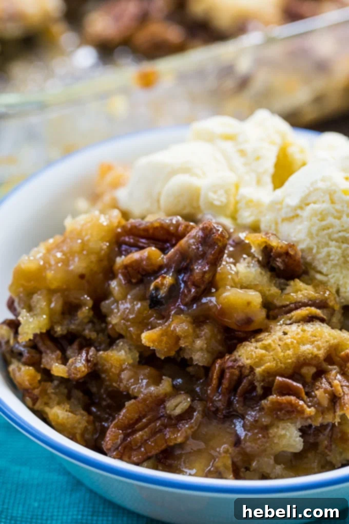 Close-up of a serving of Pecan Pie Cobbler, highlighting its rich, caramel layers and crunchy pecans.