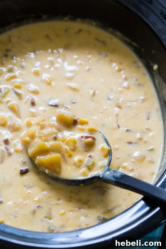 Slow Cooker Ham and Corn Chowder simmering in the pot, showcasing its hearty ingredients.