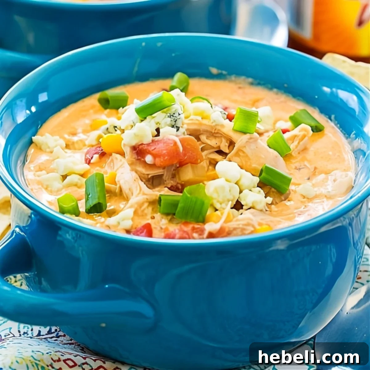 A steaming bowl of creamy Crock Pot Buffalo Chicken Chili, garnished with blue cheese crumbles and green onions, ready to be enjoyed.