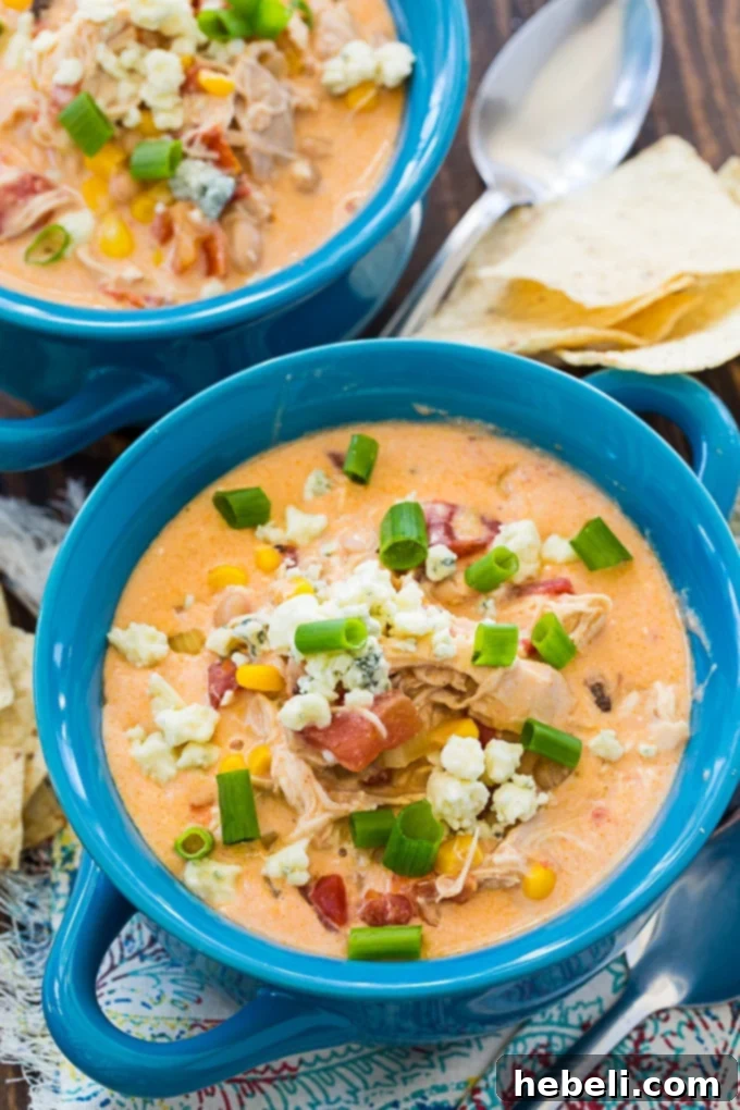 A close-up of a finished bowl of Crock Pot Buffalo Chicken Chili, adorned with vibrant green onions and crumbled blue cheese.