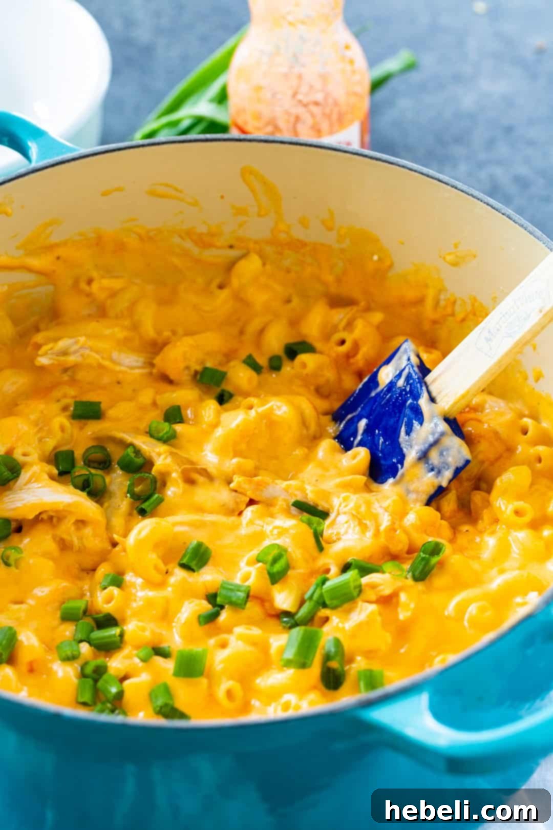 Rich and creamy Buffalo Chicken Mac and Cheese simmering in a vibrant blue Dutch oven on a stovetop.