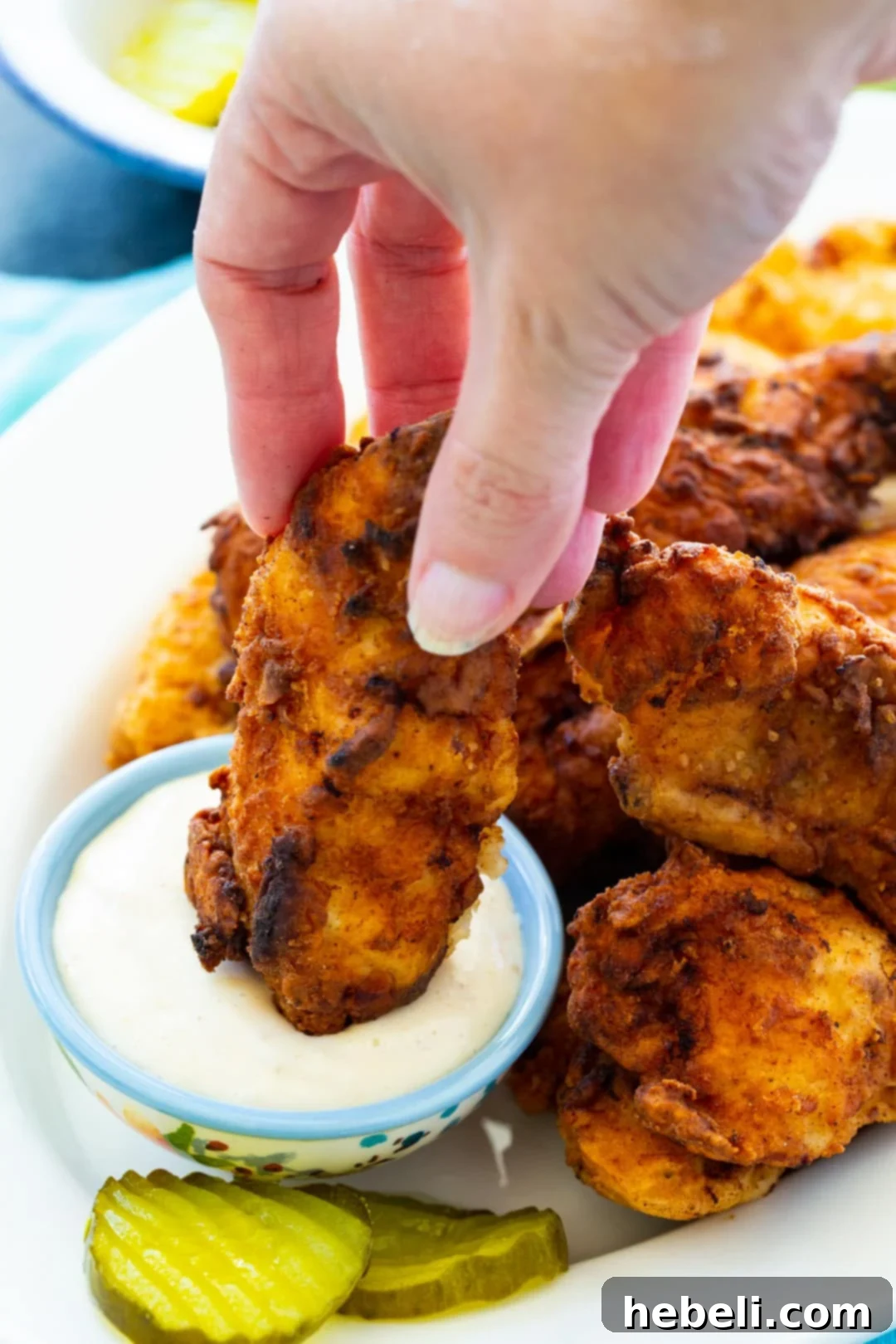 Dill Pickle Chicken Tenders 4 Pickle-Brined Chicken Tenders on plate with small bowl of dipping sauce and pickle slices.