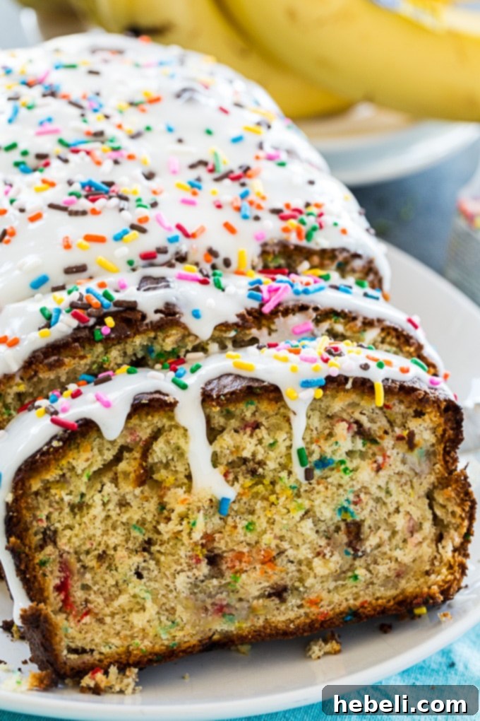 A close-up of a slice of Funfetti Banana Bread, showing the moist interior and colorful sprinkles.