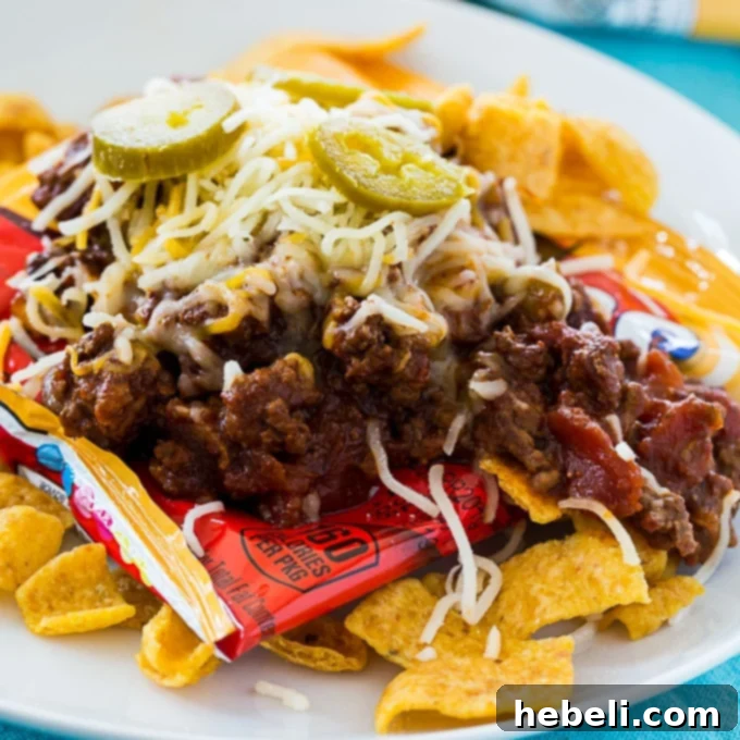 Frito Fiesta in a Pouch 2 Frito Pie in a Bag: A snack-sized bag of Frito chips generously topped with a rich, bold Texas-style chili, melted cheese, and fresh garnishes like jalapenos and onions.