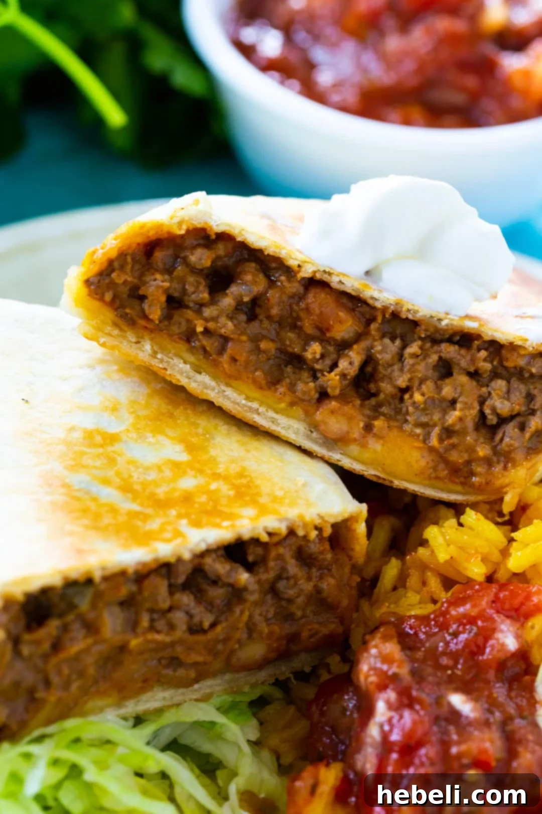 Hearty Beef & Bean Burritos 3 A delicious Beef and Bean Burrito cut in half, showcasing the layered filling of ground beef, refried beans, Mexican rice, and melted cheese.