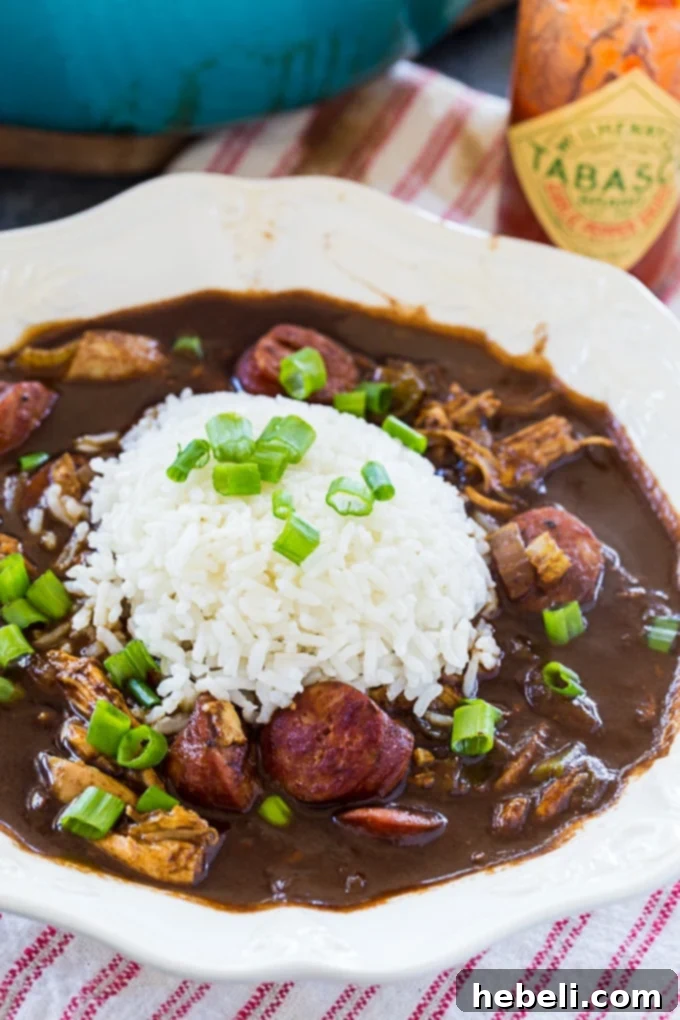 Gumbo in 30 Minutes 5 A bowl of hot 30-Minute Gumbo, served over rice and garnished with fresh green onions, showcasing its rich texture and inviting steam.