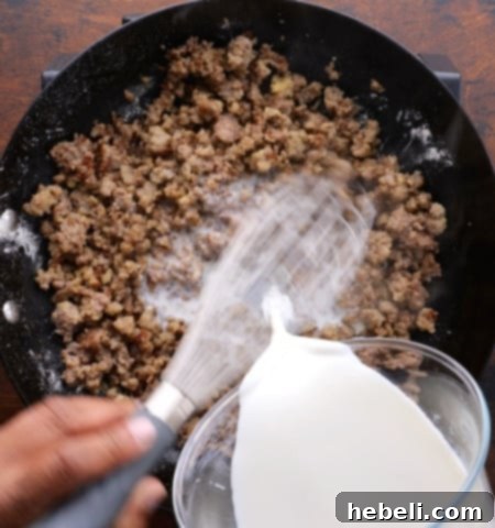 Sausage Gravy Stuffed Biscuit Cups 4 Image showing milk being gradually whisked into the sausage and flour mixture to create creamy gravy