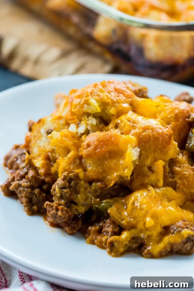Closeup of a scoop of Sloppy Joe Tater Tot Casserole, showing the layers of savory meat, melted cheese, and crispy tots on a plate.