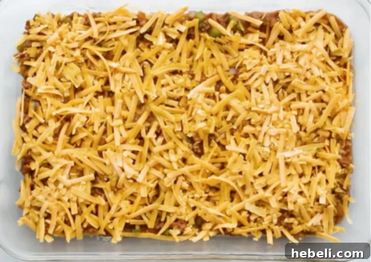 First layer of shredded cheese generously applied over the sloppy joe mixture.