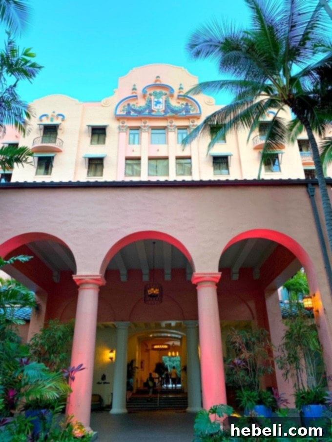 Facade of Royal Hawaiian in Waikiki showcasing its iconic pink architecture against a tropical sky
