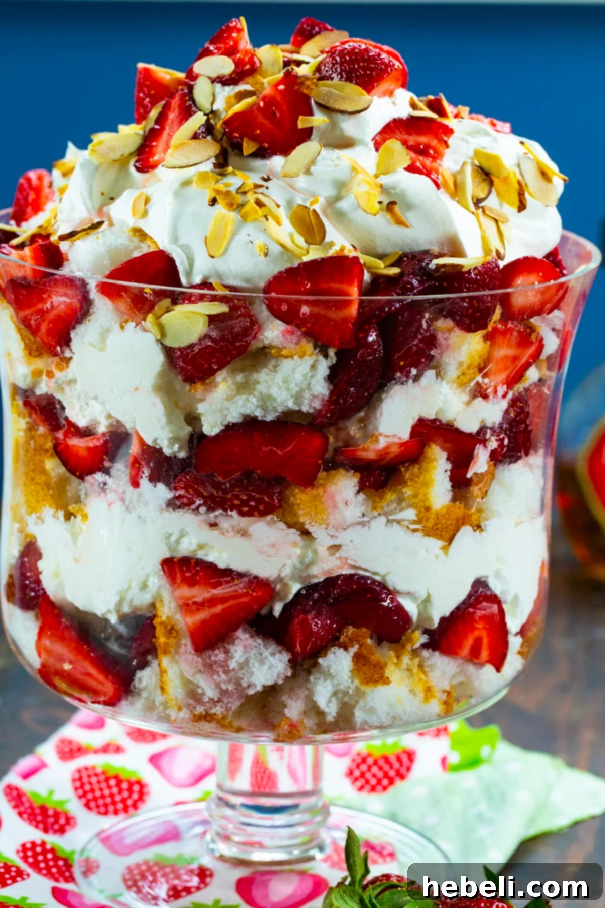 Velvet Amaretto Strawberry Trifle 5 A beautifully set Strawberry Amaretto Trifle in a decorative glass trifle dish, showcasing its meticulously crafted layers from the side, ready for a spring or summer gathering.