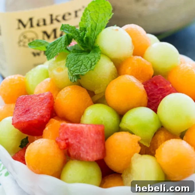 A vibrant bowl of Mint Julep Fruit Salad, featuring colorful melon balls infused with mint and bourbon, perfect for spring festivities.