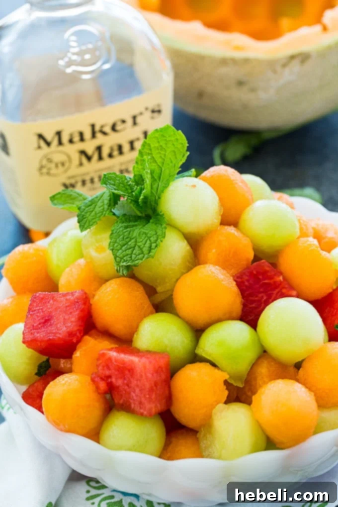 Close-up of Mint Julep Fruit Salad in a serving bowl, highlighting the glistening melon pieces and fresh mint garnish.