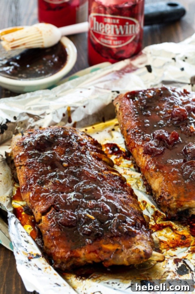 Glazed baby back ribs on a baking sheet, fresh out of the broiler with a rich, sticky coating.