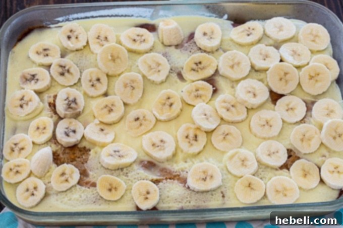 Luscious Banana Pudding Poke Cake 4 Freshly sliced ripe bananas meticulously arranged on top of the moist banana cake, forming a delicious layer.