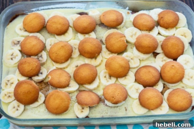 Luscious Banana Pudding Poke Cake 5 A layer of crunchy vanilla wafers carefully placed over the bananas on the poke cake, adding texture and flavor.