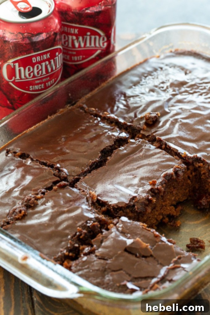 A large slice of Cheerwine Chocolate Cake with a glossy glaze, ready to be enjoyed.
