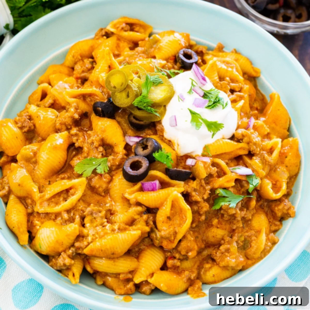 A vibrant bowl of Instant Pot Cheesy Taco Pasta, generously garnished with fresh cilantro and a dollop of cool sour cream, ready to be served.