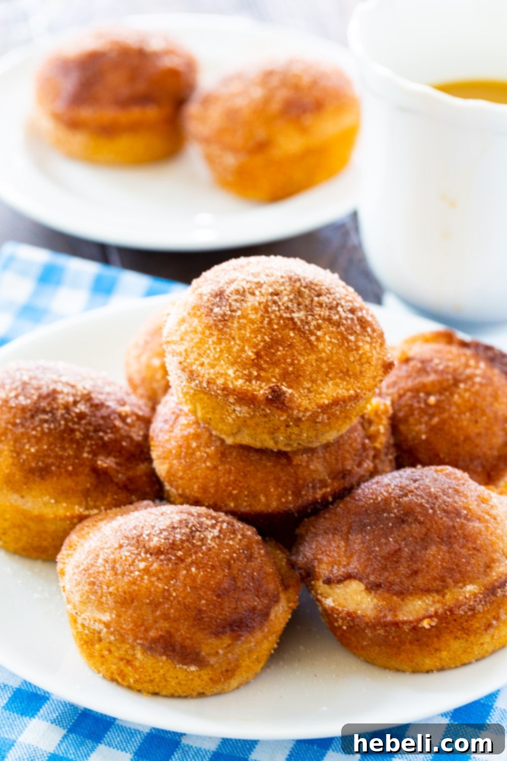 Freshly baked Old-Fashioned Doughnut Muffins on a plate next to a cup of coffee, ready to be enjoyed.