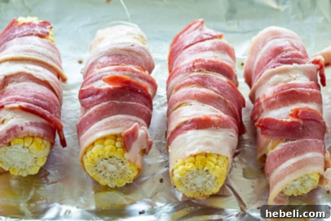 Fiery Bacon Corn Wraps 3 Fresh corn cobs meticulously wrapped in bacon slices, ready for roasting.