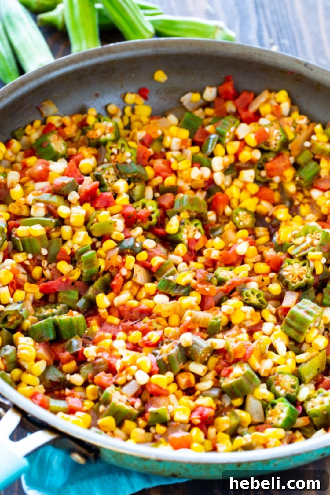 Corn Okra Creole simmering gently in a large, hot skillet, with steam rising, illustrating the cooking process and rich textures of the vegetables.