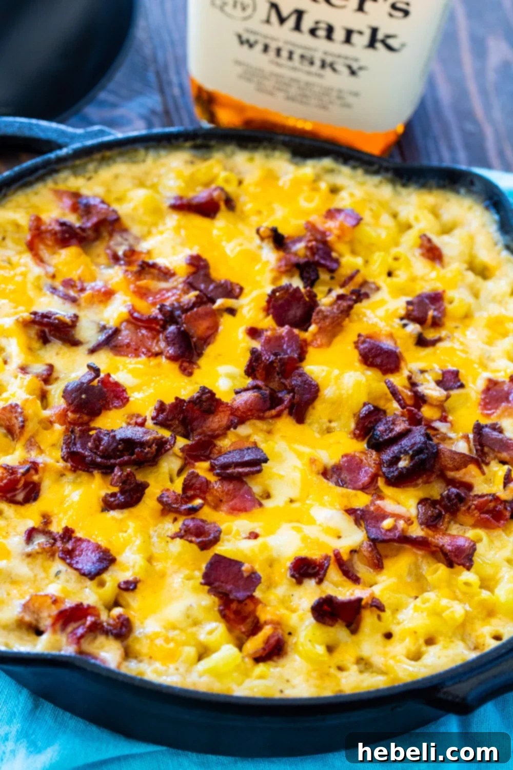Close-up view of Bourbon and Bacon Mac and Cheese, generously topped with crispy bacon bits, bubbling in a cast iron pan.