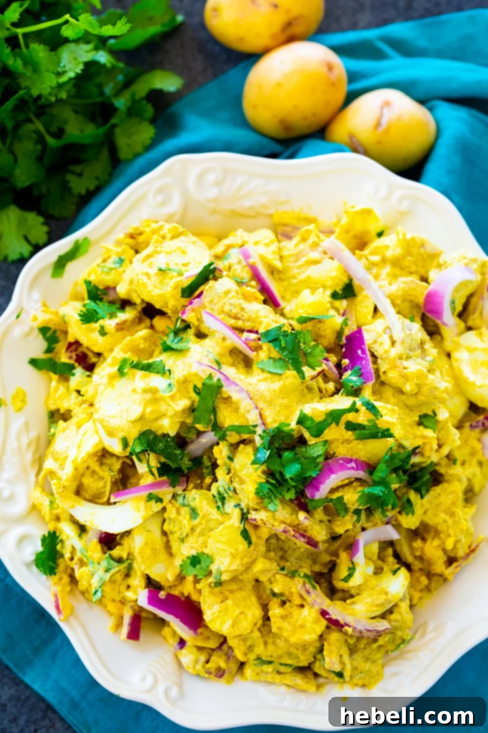 Overhead view of Curried Potato Salad in a decorative bowl, showcasing its creamy texture and vibrant ingredients.