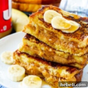 Peanut Butter Stuffed French Toast stacked on a plate with fresh fruit.