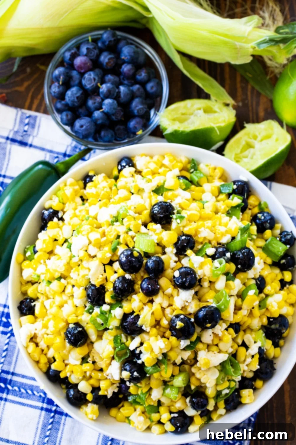 Vibrant Blueberry Corn Feta Salad 3 Blueberry, Corn and Feta Salad in a bowl, surrounded by fresh blueberries and lime halves, highlighting its fresh ingredients.