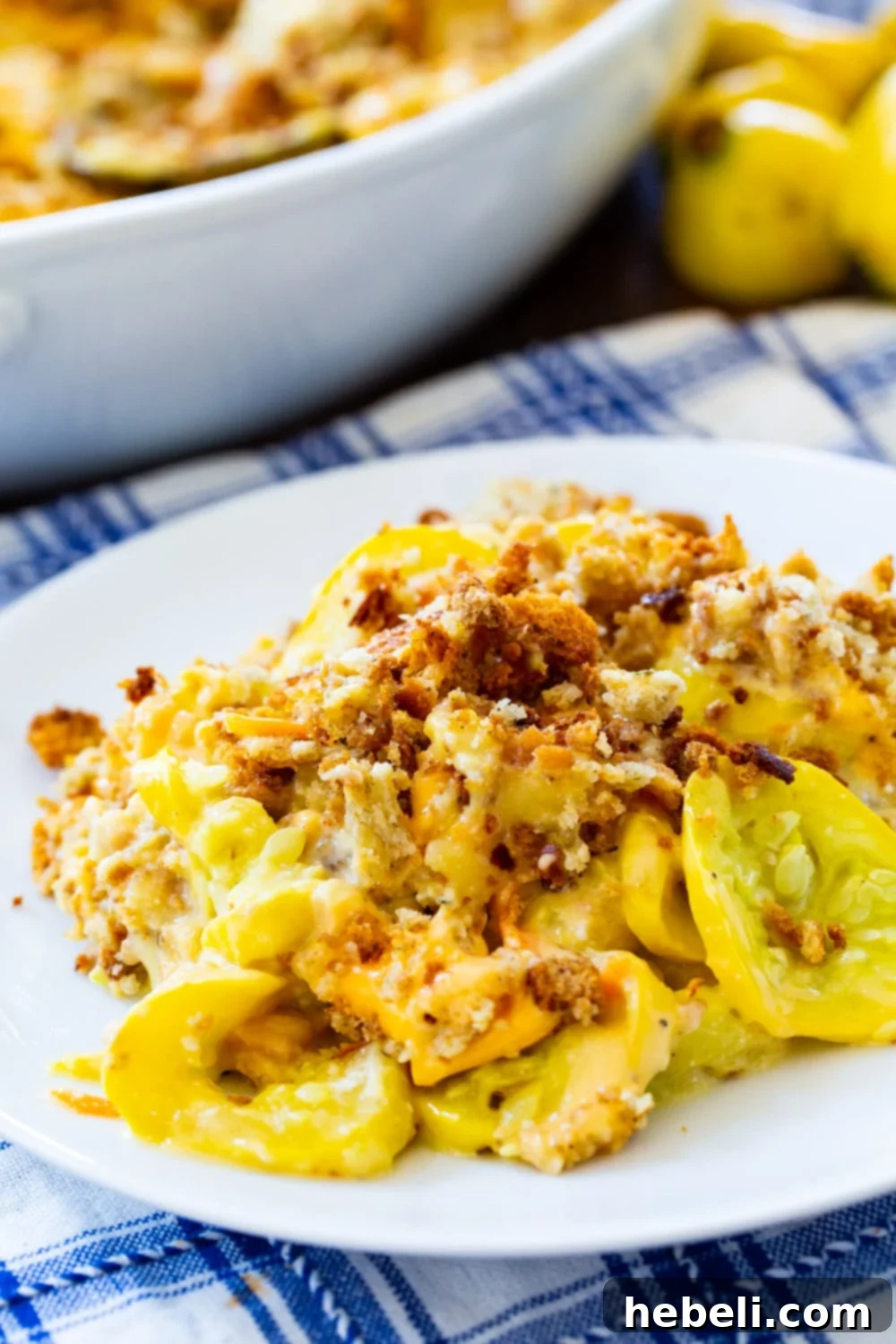 Stuffing-Topped Squash Casserole 5 A generous serving of Squash Casserole with Stuffing Top on a white plate, garnished with fresh herbs.