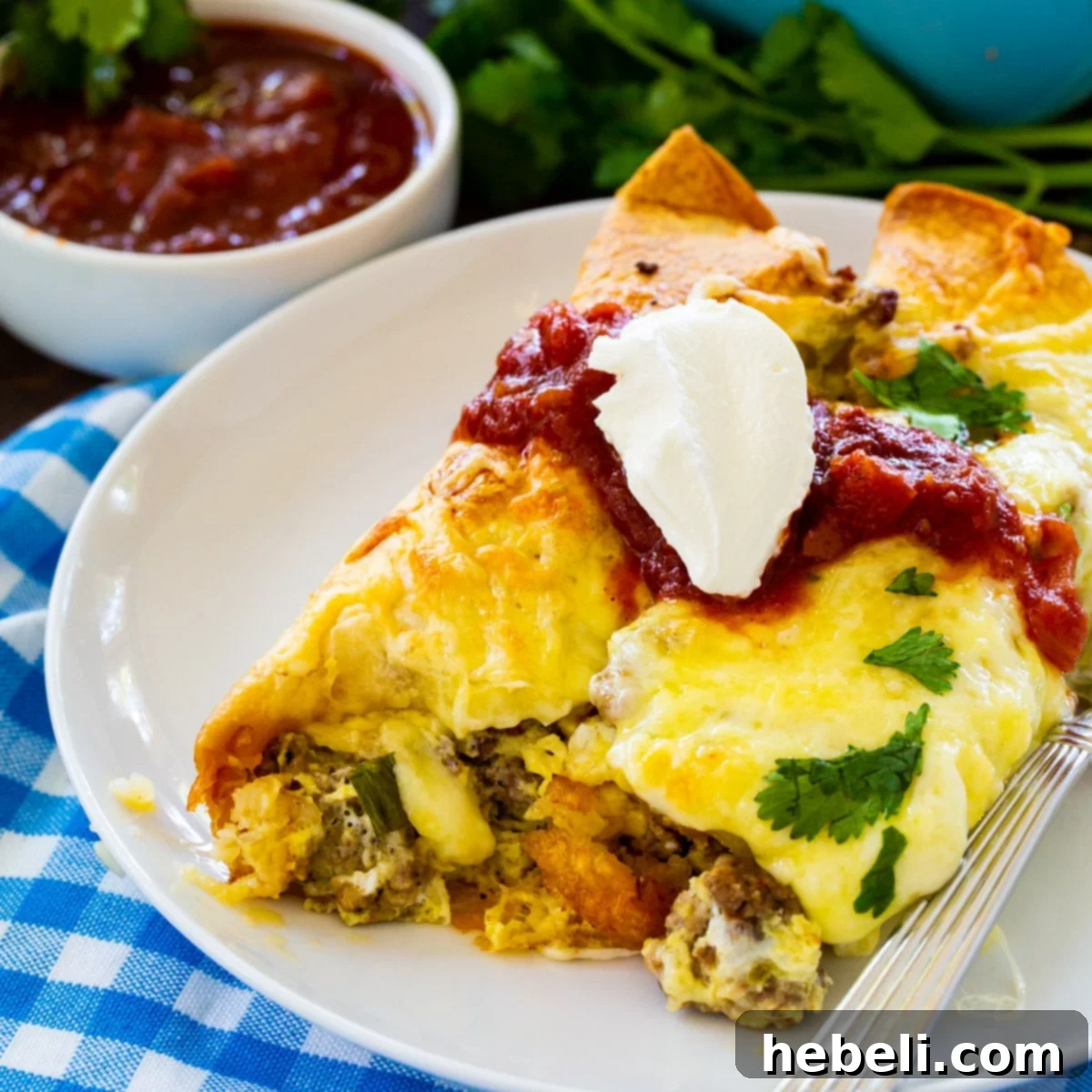 Fiery Sausage Morning Enchiladas 2 Two Spicy Sausage Breakfast Enchiladas on a plate, garnished with fresh cilantro and a dollop of sour cream, ready to be enjoyed.