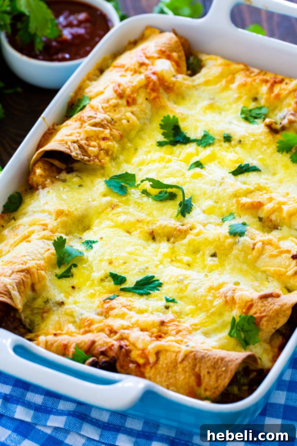 Fiery Sausage Morning Enchiladas 3 Breakfast Enchiladas baking in a 9x13-inch casserole dish, golden and bubbly, with cheese melting over the top.