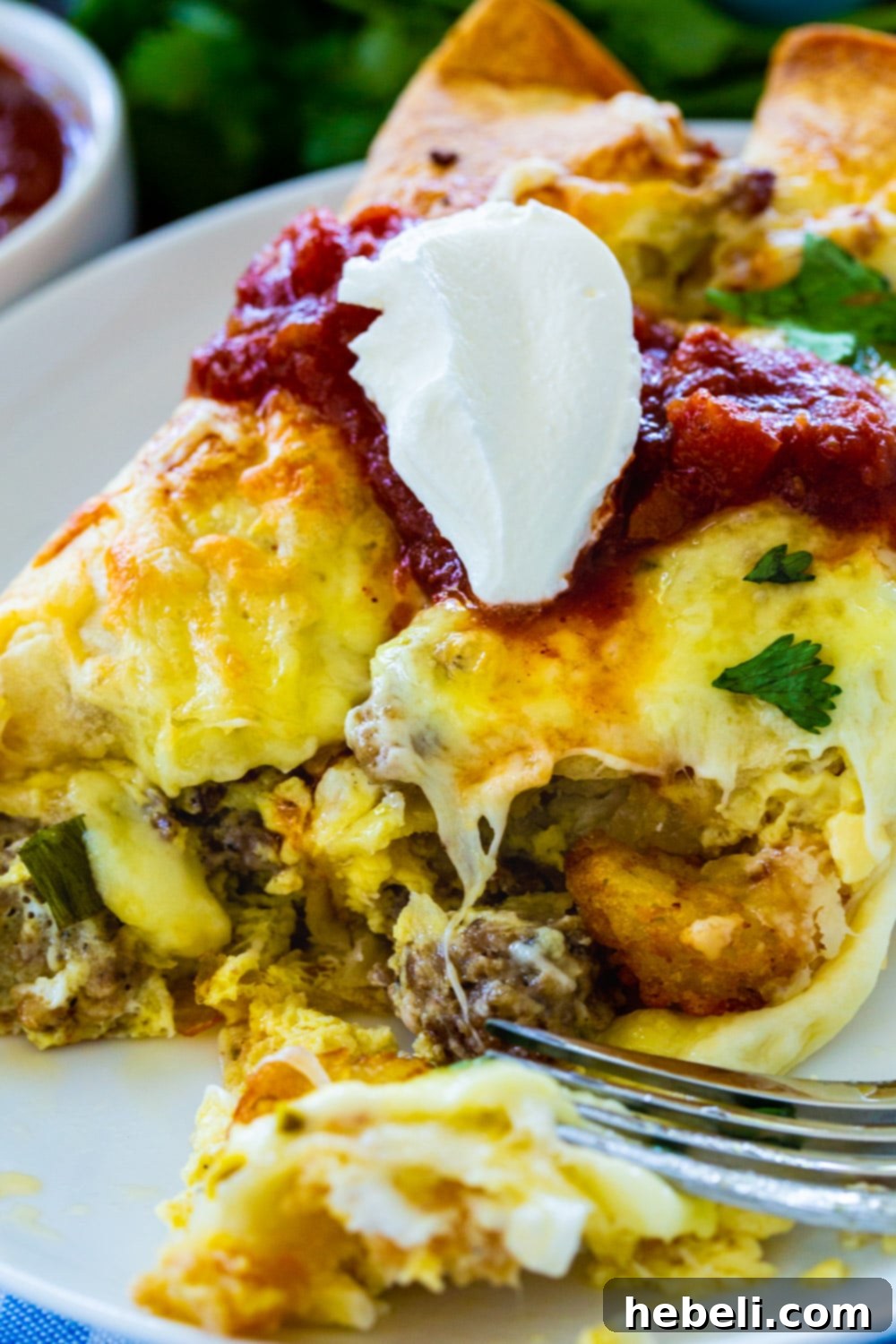Fiery Sausage Morning Enchiladas 4 A fork cutting into a Spicy Sausage Breakfast Enchilada, revealing the creamy filling of sausage, tater tots, and cheese inside.