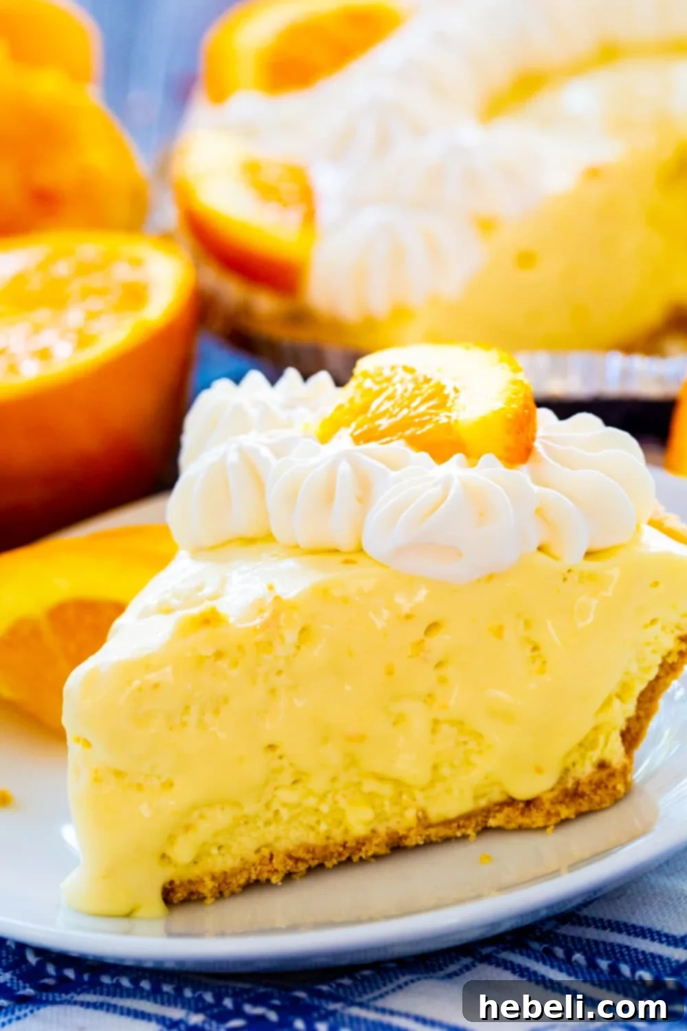 Another close-up shot of a slice of Orange Creamsicle Pie on a white plate, highlighting the creamy filling and crisp golden graham cracker crust, perfect for a summer treat.