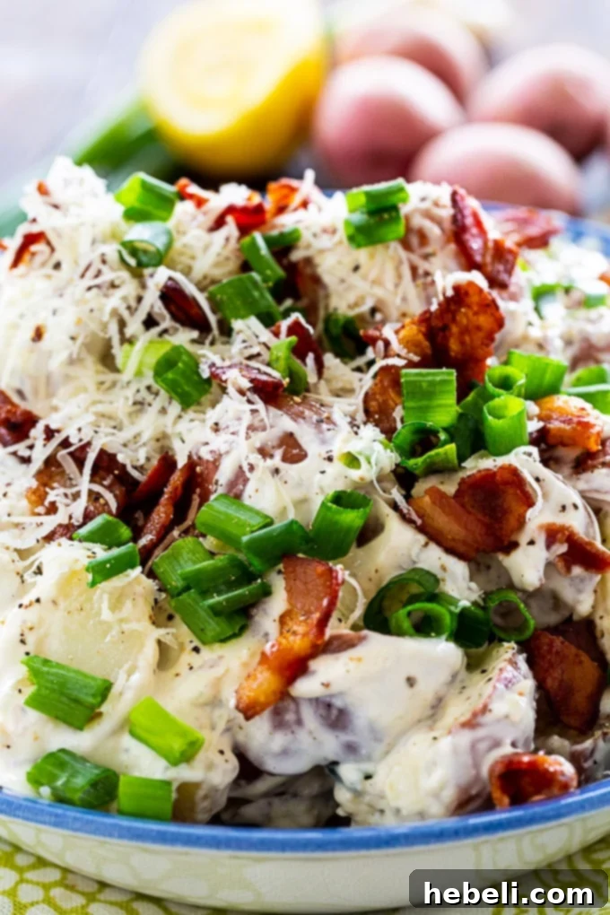 Individual serving of Caesar Potato Salad in a white bowl, garnished with green onions