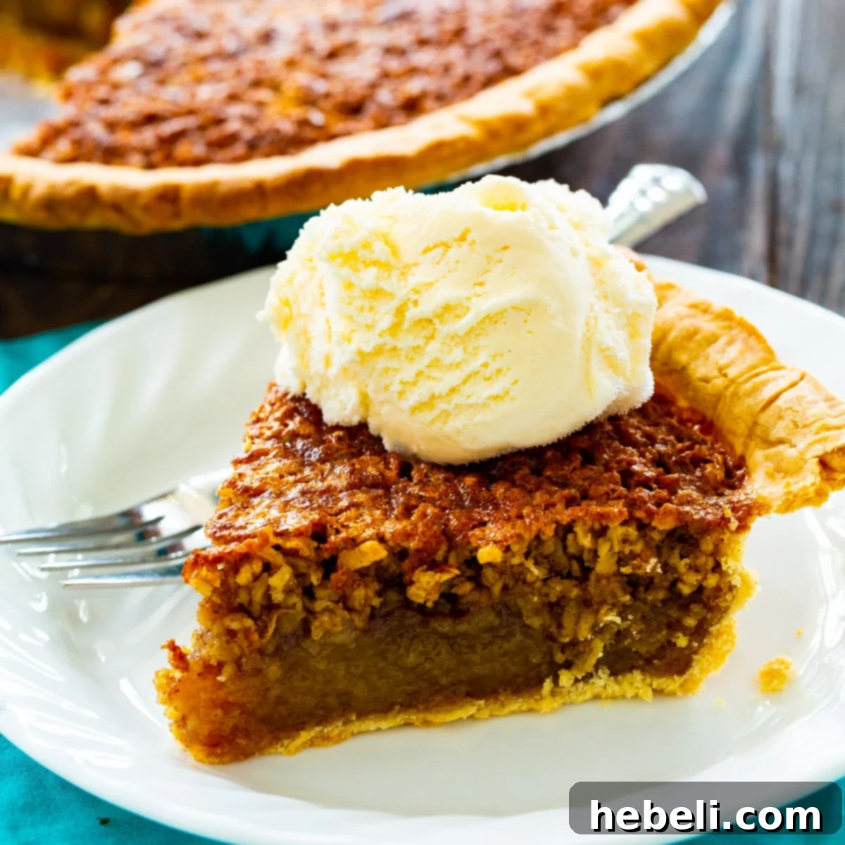 Slice of Oatmeal Pie topped with vanilla ice cream, showing its gooey texture and oat flakes.