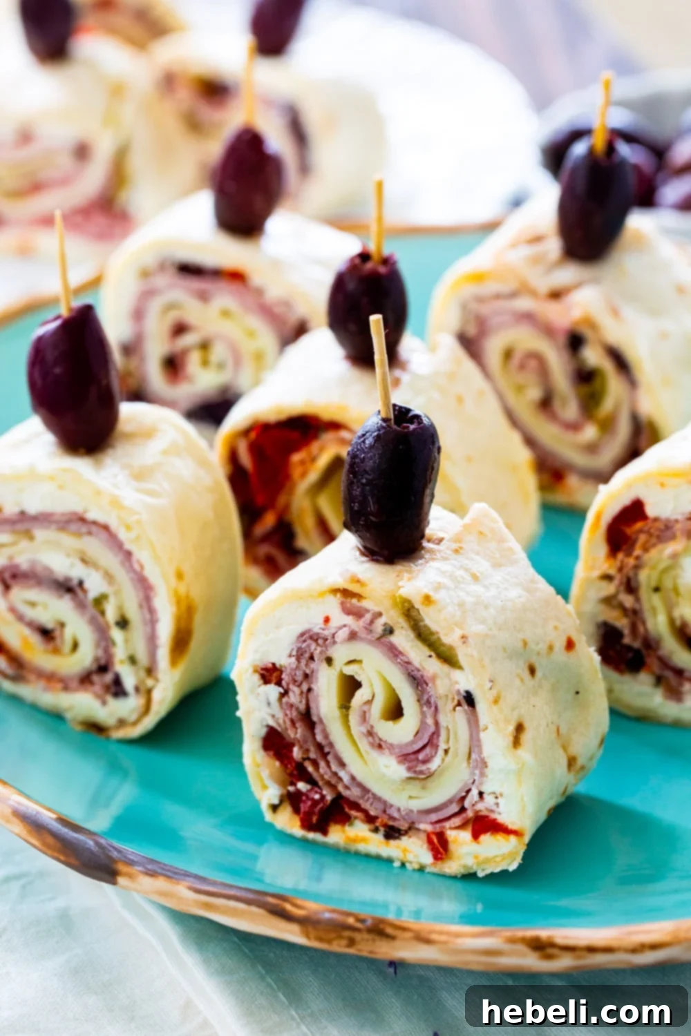 Assortment of vibrant Muffaletta Pinwheels artfully arranged on a blue serving plate.
