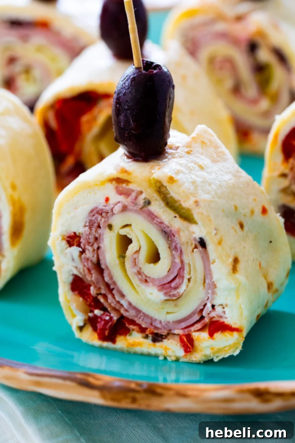 Close-up view of a single, perfectly sliced Muffaletta Pinwheel revealing its layered ingredients.