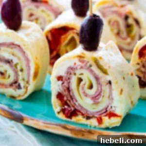 Muffaletta Pinwheels topped with black olives on a plate.