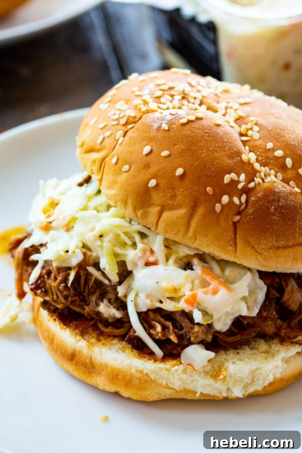 Close-up of shredded Instant Pot Pulled Pork piled high on a bun with a side of fresh coleslaw.