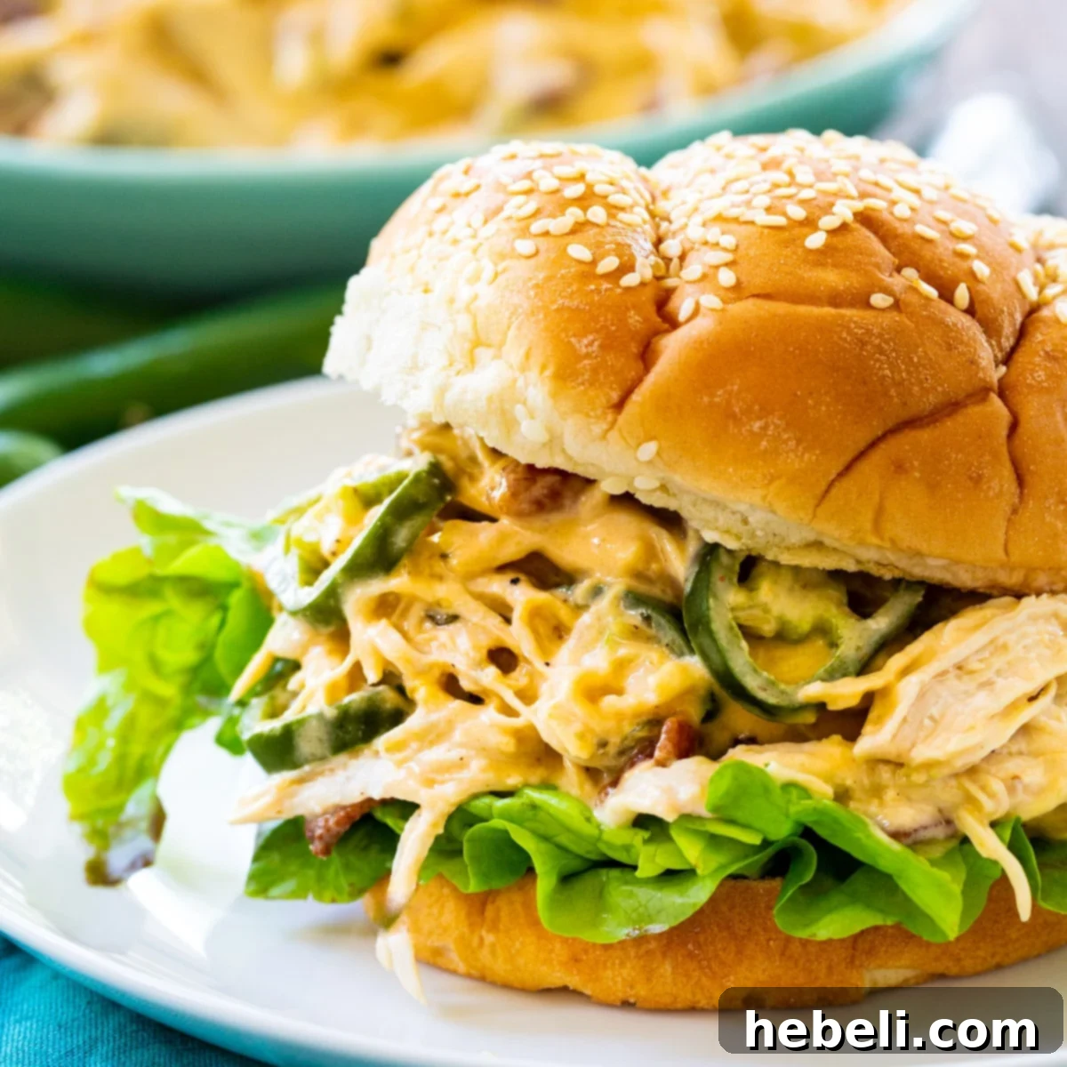 Delicious Instant Pot Jalapeno Popper Shredded Chicken served on a soft bun, garnished with fresh green onions and crispy bacon bits, highlighting its creamy and flavorful texture.