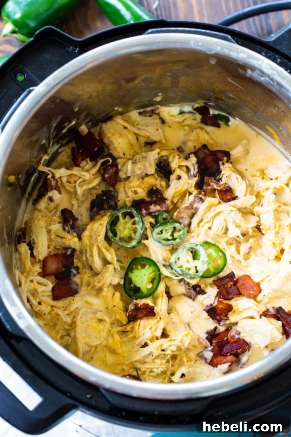 The process of preparing Jalapeno Popper Shredded Chicken inside an Instant Pot, showing chicken breasts and other ingredients before pressure cooking.