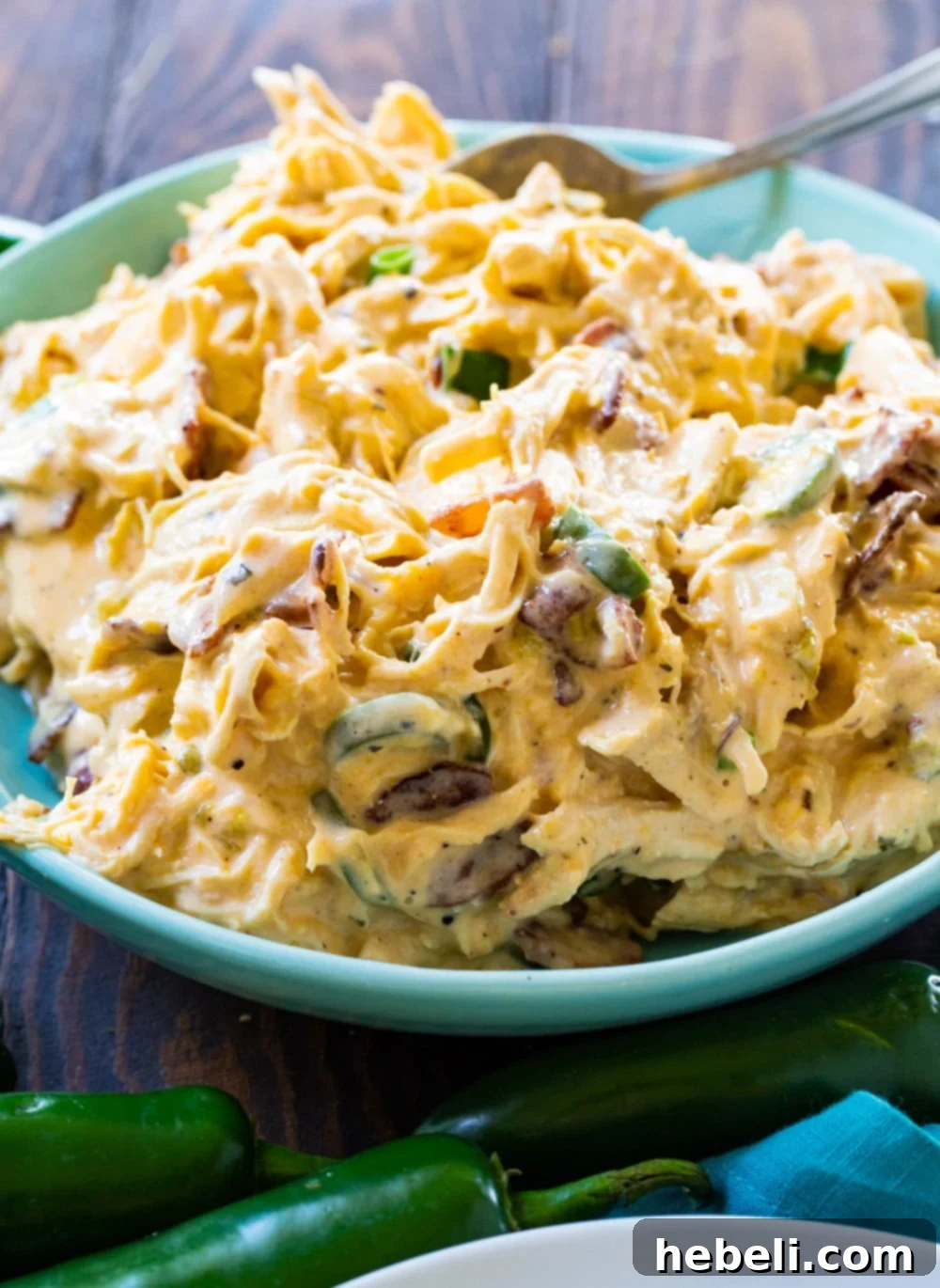 A large bowl of Instant Pot Jalapeno Popper Shredded Chicken, garnished with green onions and ready to be served, showcasing its creamy texture.