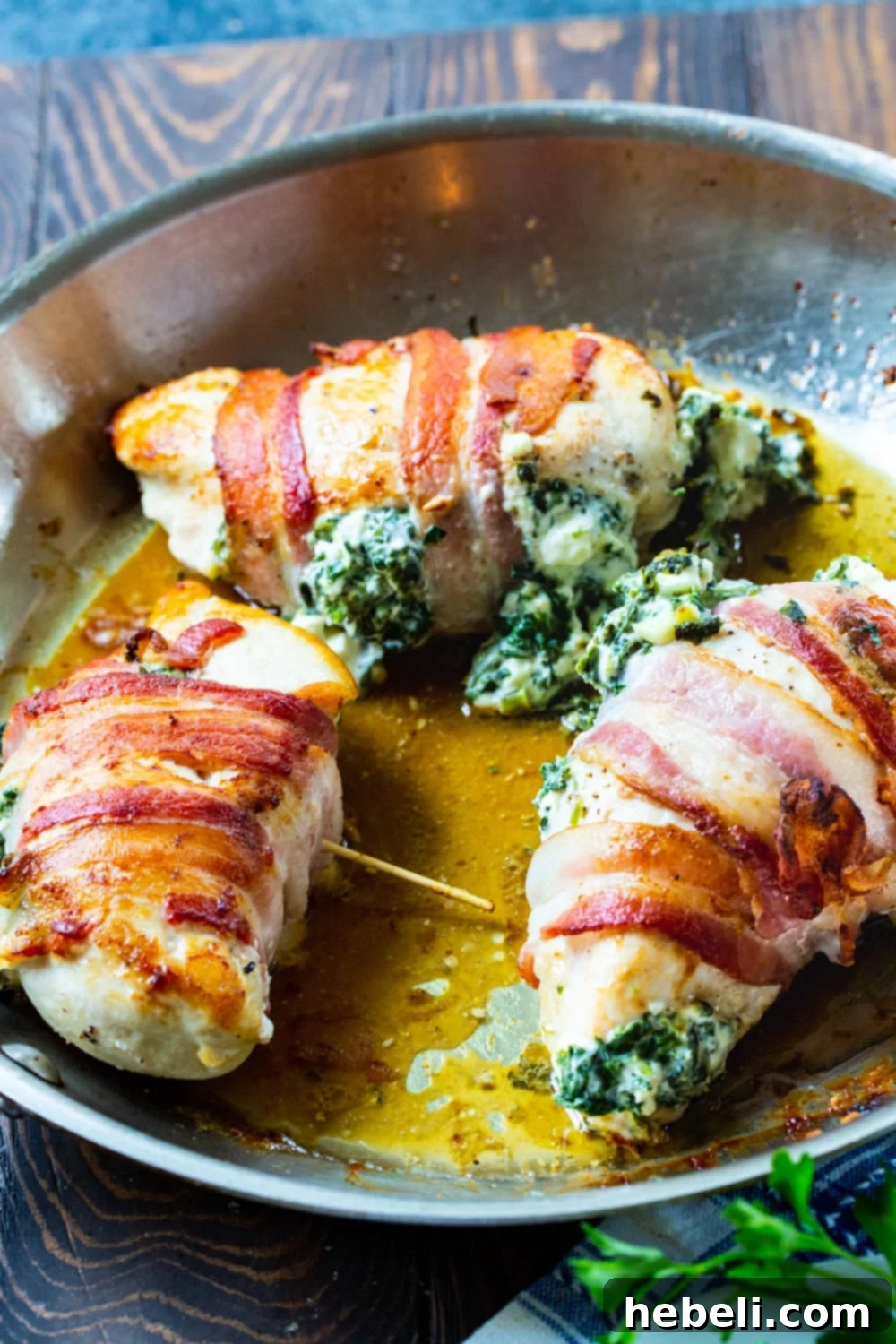 Crispy Bacon Wrapped Feta Spinach Chicken 3 Stuffed Chicken Breasts in a skillet after being cooked.