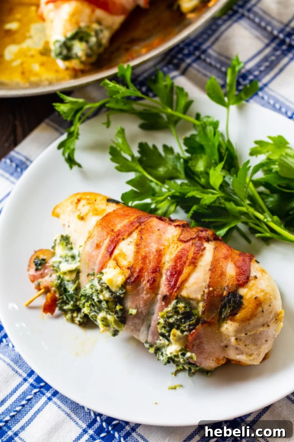 Crispy Bacon Wrapped Feta Spinach Chicken 4 Bacon Wrapped Spinach and Feta Stuffed Chicken breast on a plate.