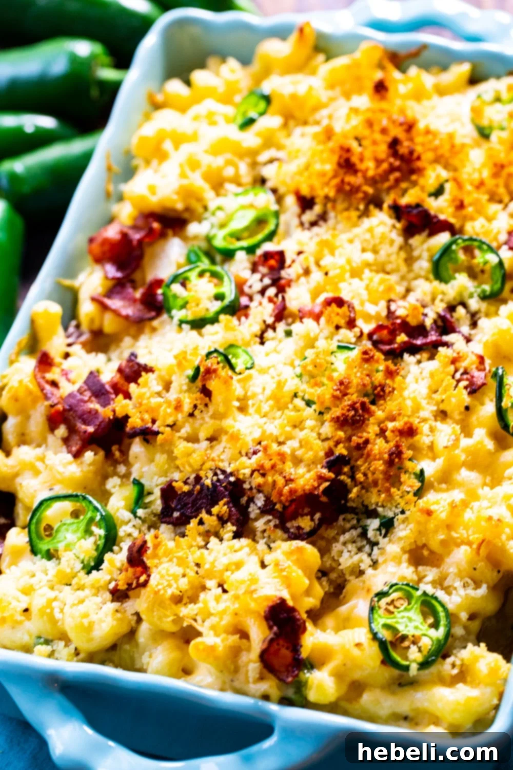 Close-up shot of creamy Jalapeño Popper Mac and Cheese in a baking dish, featuring visible pieces of crispy bacon, chopped jalapeños, and melted cheese, ready for the oven.