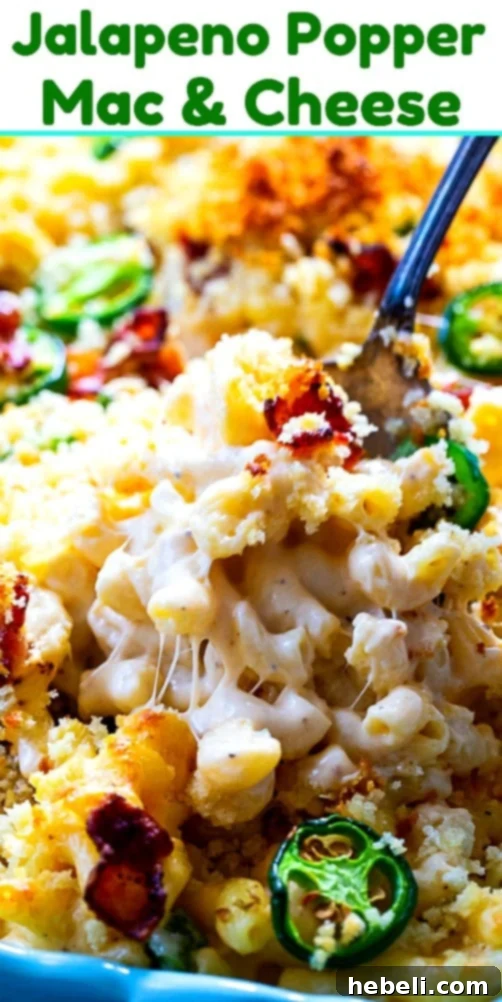 A top-down view of a freshly baked Jalapeno Popper Mac and Cheese in a rectangular baking dish, with a golden-brown Panko topping and visible bits of bacon and jalapeños.