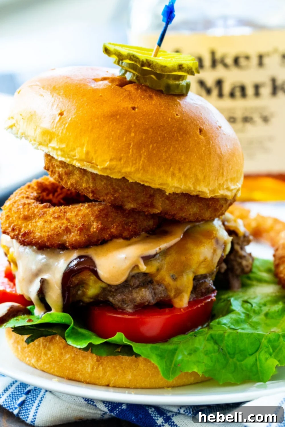 A Bourbon BBQ Burger served on a plate with fresh pickle slices on top, highlighting the juicy patty and toasted bun.