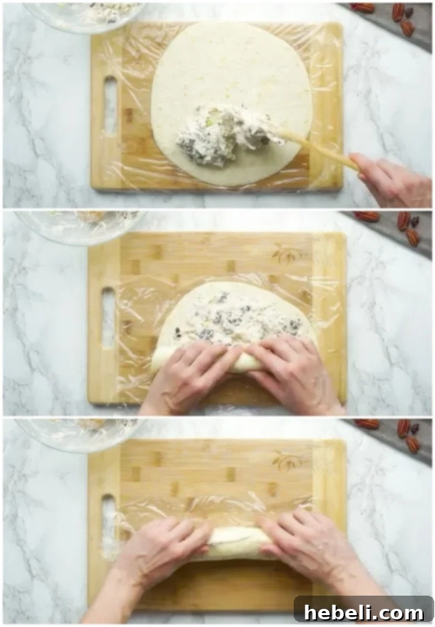 Spreading the creamy chicken cranberry mixture evenly onto a softened tortilla and rolling it up tightly to form a log.
